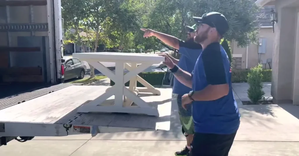 Paramount 17 Crew loading a white farmhouse table at the open tailgate