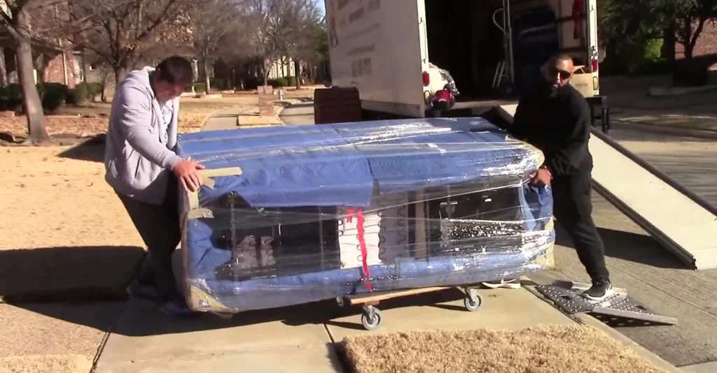 Paramount 13 Two movers rolling a wrapped sofa on a dolly to the truck ramp in Amarillo, TX