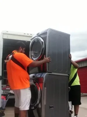Paramount 8 Two movers lifting a stacked washer and dryer beside the moving truck