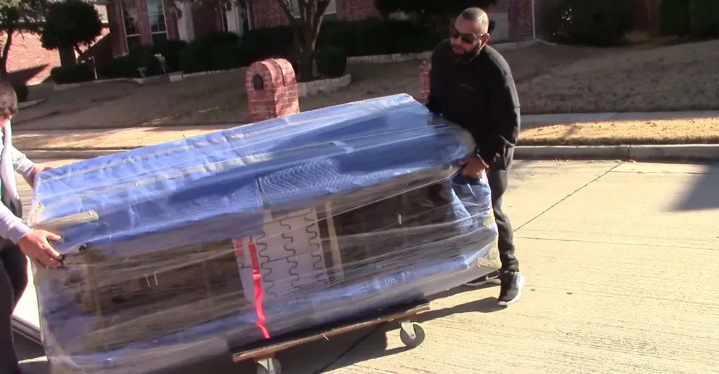 Paramount 15 Two movers rolling a blanket-wrapped sofa on a dolly along the curb